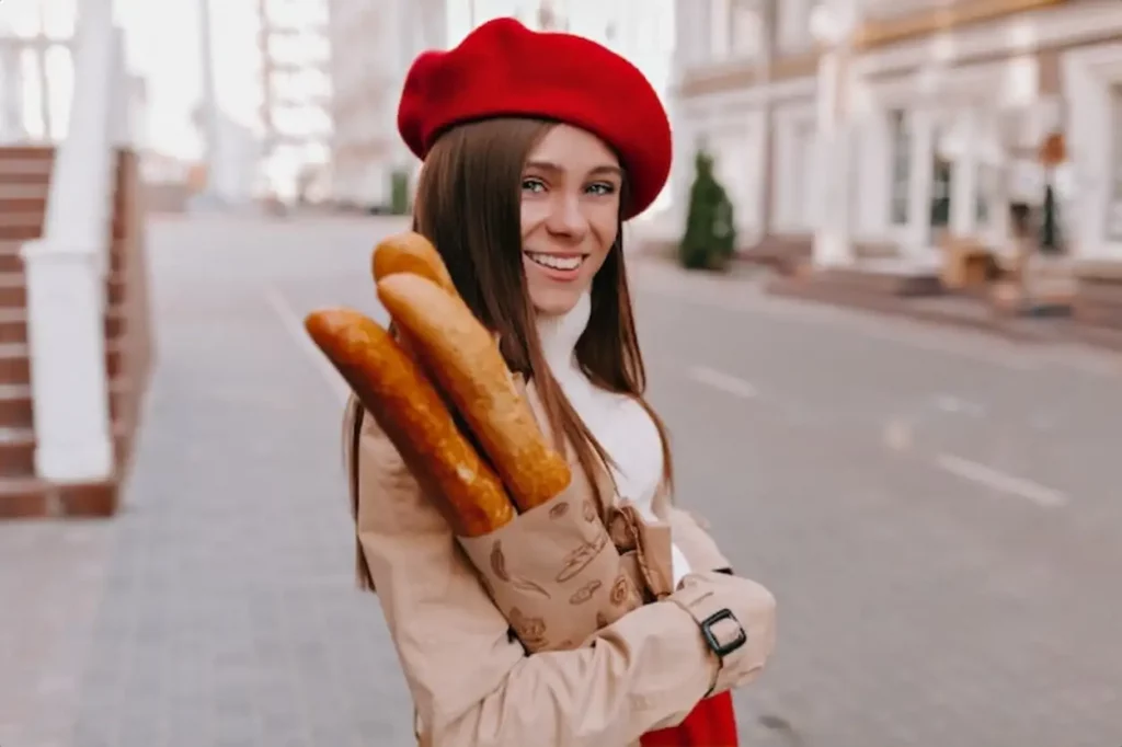 Smiling girl walking outdoor in sunny morning and holding baguette.