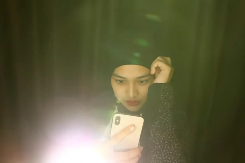 Young woman doing selfie against black background