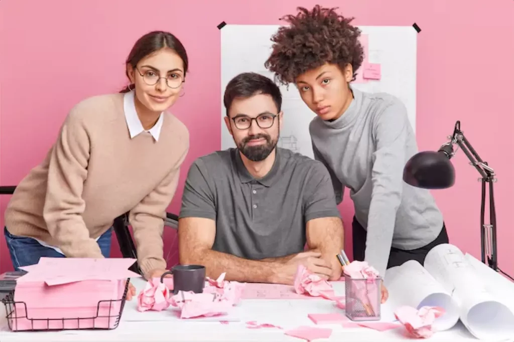 Three young motivated people discuss plan of cooperation on common architectural project poses in modern coworking office collaborate for making research
